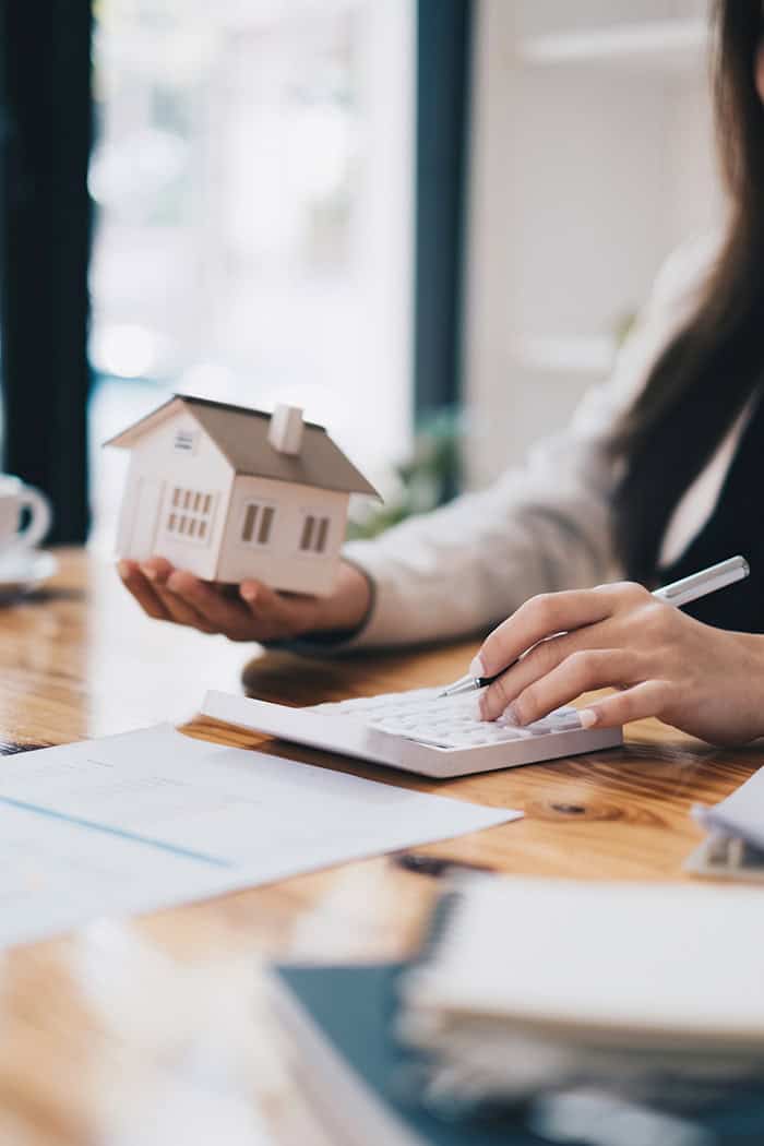 Prestige Settlement agent discussing home settlement with client, holding a house model.